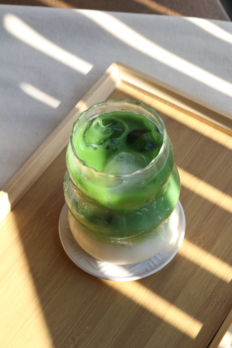 Matcha latte on a wooden tray with a shadow on top